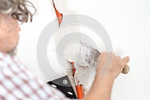 Electrician plastering recessed wiring in a wall