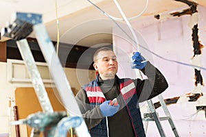 Electrician with pliers in hand prepares electrical wiring in house under construction