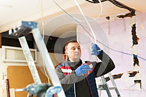 Electrician with pliers in hand prepares electrical wiring in house under construction