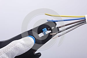 An electrician prepares the cable for connection, removes the insulation with a stripper