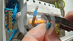 An electrician putting blue bushing ferrules on wires and clamping them. Macro shot of mans hand repairing high voltage