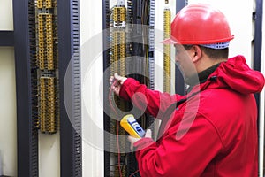 Electrician in red control circuit with multimeter