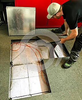 Electrician removes floor panels to get to cables