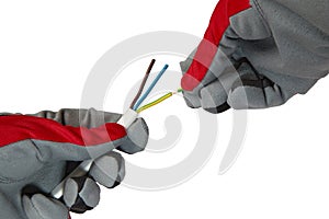 An electrician removes insulation from a three-core copper wire. Hands in protective gloves and electric cable isolated