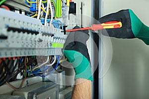 Electrician repairing fuse box with screwdriver, closeup