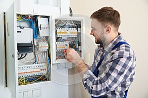 Electrician repairing fuse box with screwdriver photo