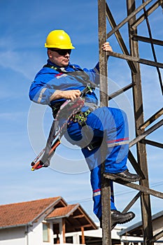 Electrician with safety belt working on electric power pole