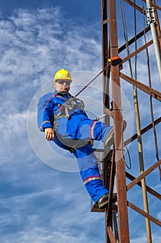 Electrician with safety belt and yellow helmet on electric pole