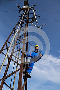 Electrician with safety belt and yellow helmet on lamppost photo