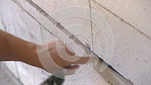 Electrician securing cables in groove or chase on a wall in newly built house, using power drill and screws - closeup detail