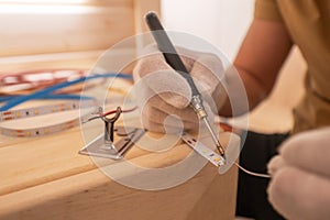 Electrician with Soldering Iron Attaching LED Stripe Cable