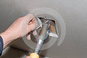The electrician solders the twisted electrical wires in the socket with a belt. Installation of communications and insulation of