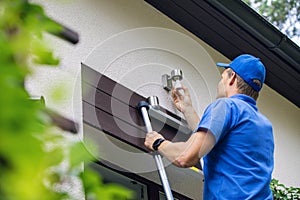 Electrician standing on ladder and change the light bulb