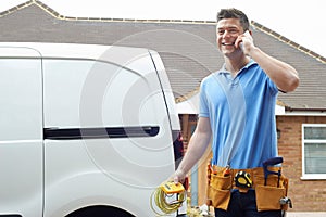 Electrician Standing Next To Van Talking On Mobile Phone