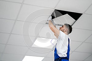 Electrician On Stepladder Installs Lighting To The Ceiling