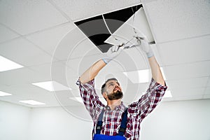 Electrician On Stepladder Installs Lighting To The Ceiling