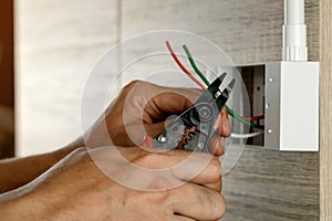 Electrician is stripping electrical wires in a plastic box.