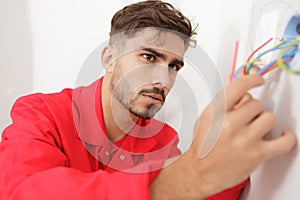 electrician technician fixes electric cable to socket