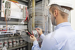 Electrician technician in fuse box. Maintenance engineer in control panel. Worker is testing automation equipment