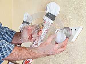 Electrician technician at work installs the new energy-saving LED bulb.