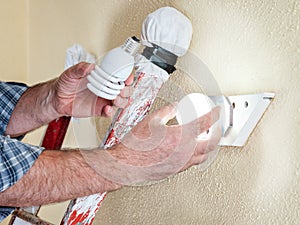 Electrician technician at work installs the new energy-saving LED bulb.