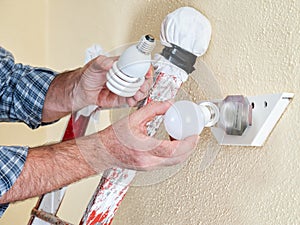 Electrician technician at work installs the new energy-saving LED bulb.