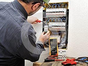 Electrician technician at work with protective helmet on a residential electric panel photo