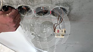 Electrician technician worker dismantles an old socket and fixes the wires