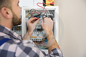 Electrician with tester checking voltage indoors