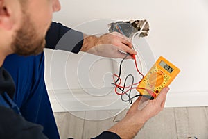 Electrician with tester checking voltage indoors