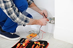 Electrician with tester checking voltage indoors