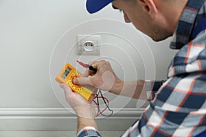 Electrician with tester checking voltage indoors, closeup