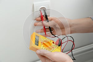 Electrician with tester checking voltage indoors, closeup