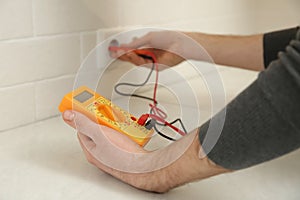 Electrician with tester checking voltage indoors, closeup