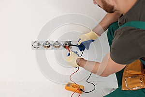 Electrician with tester checking voltage indoors, closeup