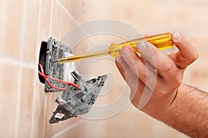 Electrician testing for electricity in electrical wall fixture