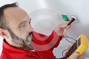 electrician testing plug socket with multimeter