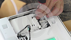 An electrician tightens a screw in the body of an electrical appliance.