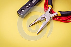 Electrician tools and wire on yellow background for repairing energized systems or communications