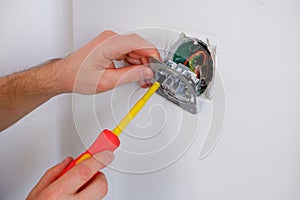 The electrician unscrews the switch with a screwdriver. Close-up on the hands. The routine work of an electrician. Checking