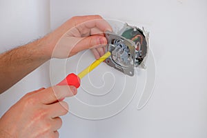 The electrician unscrews the switch with a screwdriver. Close-up on the hands. The routine work of an electrician. Checking