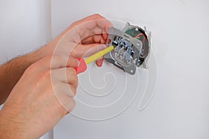 The electrician unscrews the switch with a screwdriver. Close-up on the hands. The routine work of an electrician. Checking