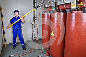 Electrician uses an discharge stick to earth transformer. photo