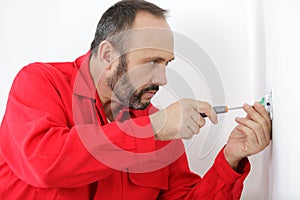 electrician using screwdriver on plug socket