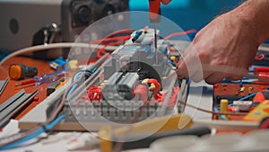 Electrician using a screwdriver is screwing a red wire in an automatic electrical switch. Close up of a mans hands