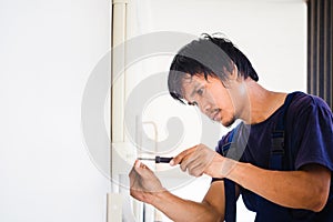 Electrician using a screwdriver, Technician installing air conditioning in a client house, Repairman fixing air conditioner unit,
