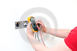 Electrician a wall socket with electronic multimeter