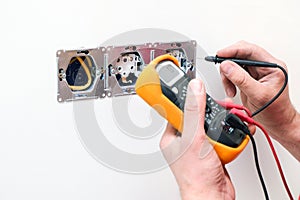 Electrician a wall socket with electronic multimeter