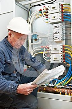 Electrician at wiring with working drawings