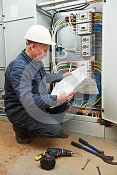 Electrician at wiring with working drawings